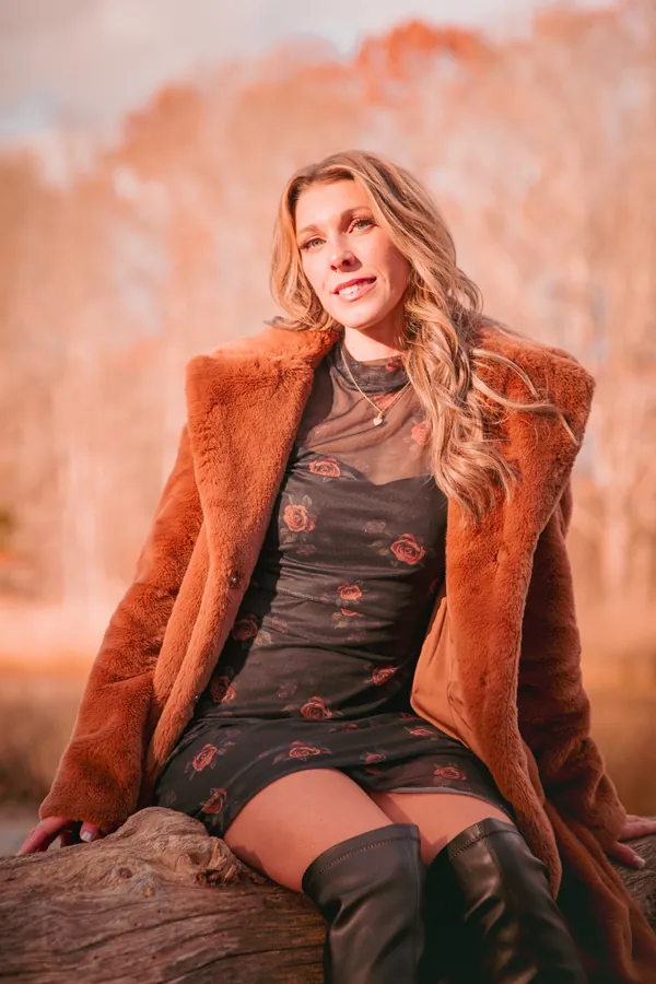 Woman in a rust coat amid autumn grasses