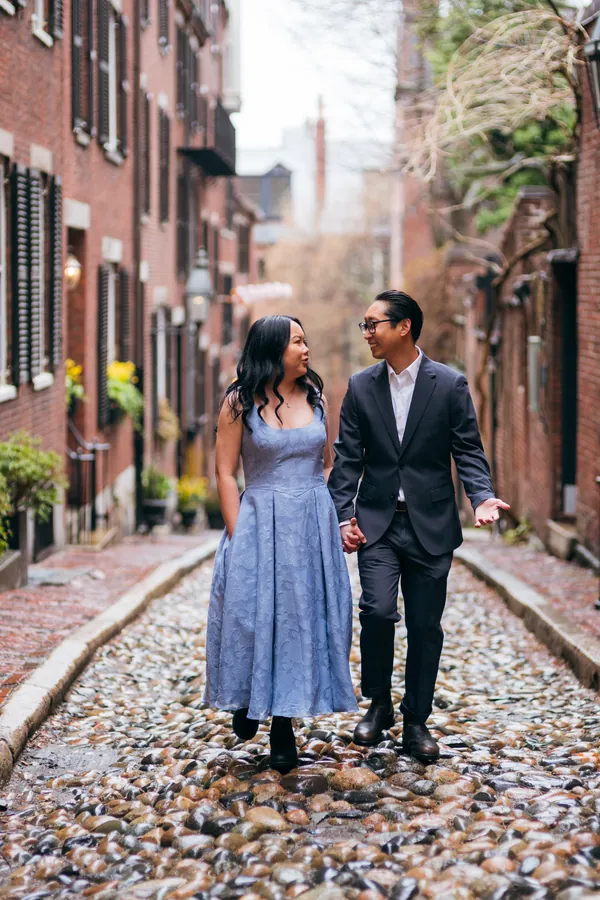 Engaged couple walking hand in hand down a cobblestone alley